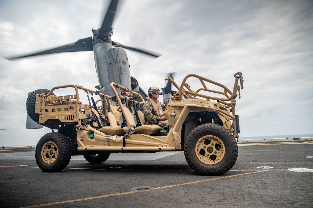 A U.S. Marine assigned to the All-Domain Reconnaissance Detachment, 11th Marine Expeditionary Unit , prepares to load a Polaris MRZR light tactical all-terrain vehicle onto an MV-22B Osprey attached to Marine Medium Tiltrotor Squadron 165, 11th MEU, on the flight deck of Wasp-class amphibious assault ship USS Essex (LHD 2) in support of Exercise Noble Fusion, Feb. 3, 2022. As a forward deployed unit capable of conducting amphibious operations, crisis response, and limited contingency operations, the 11th MEU regularly conducts training to be able to operate in contested areas to create strategic advantage while building lethality and integrated deterrence. Noble Fusion demonstrates that Navy and Marine Corps forward-deployed, stand-in naval expeditionary forces can operate as a Marine Expeditionary Unit/Amphibious Ready Group team at sea, along with a carrier strike group, in order to conduct lethal sea-denial operations, seize key maritime terrain, guarantee freedom of movement, and create advantage for U.S., partner, and allied forces.