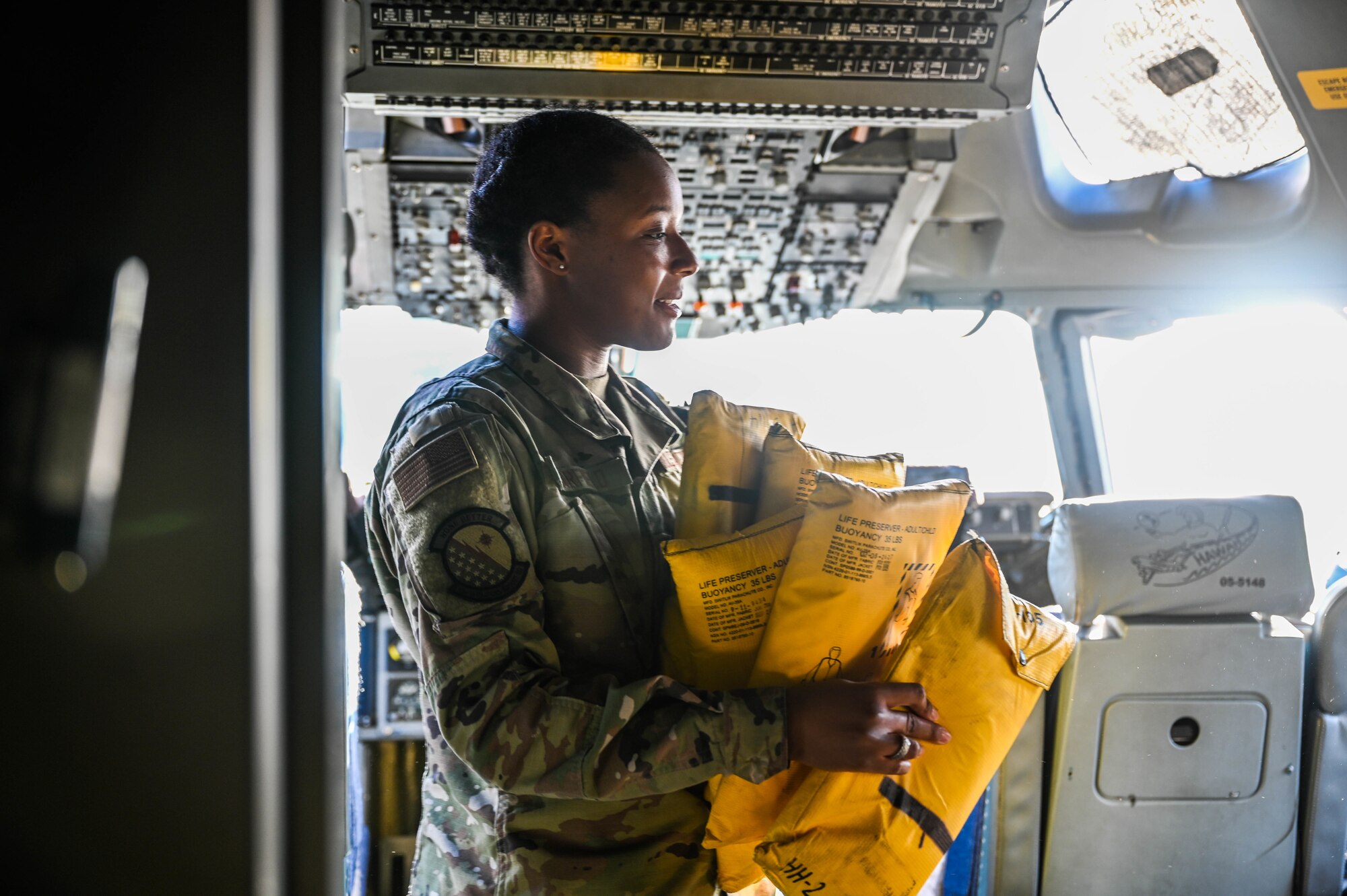 Airman 1st Class Kinnidy Warfield, 15th Operations Support Squadron aircrew flight equipment apprentice collects life jackets to perform functional checks at Joint Base Pearl Harbor-Hickam, Hawaii, Feb. 1, 2022. AFE regularly tests, inspects and prepares safety equipment located on the aircraft to ensure the safety of the aircrew and passengers. (U.S. Air Force photo by Staff Sgt. Alan Ricker)