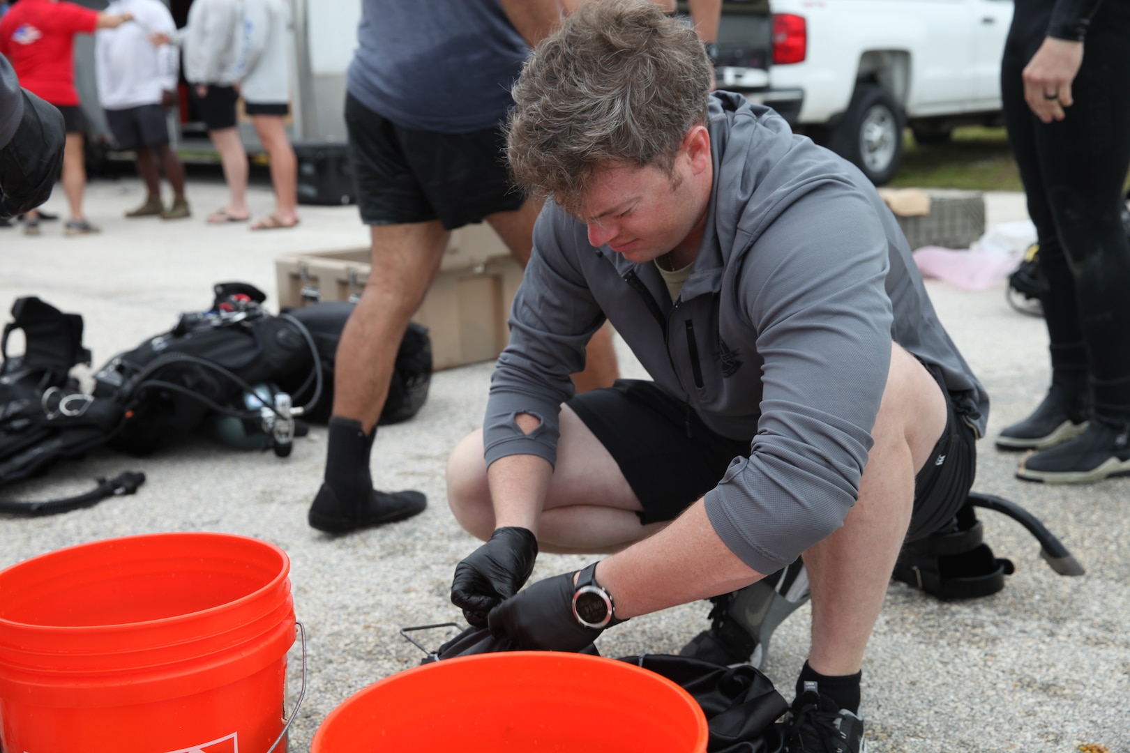 An EOD operator sorts forensic evidence in front of two orange buckets.