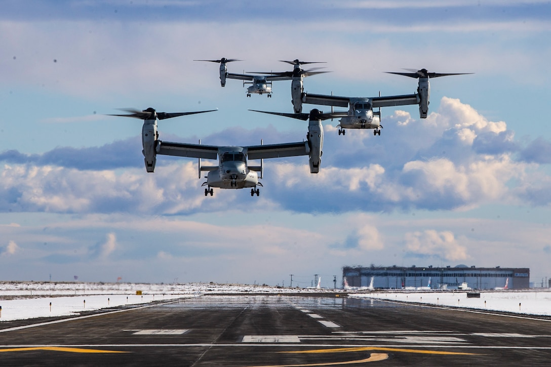 Three airborne helicopters prepare to land.