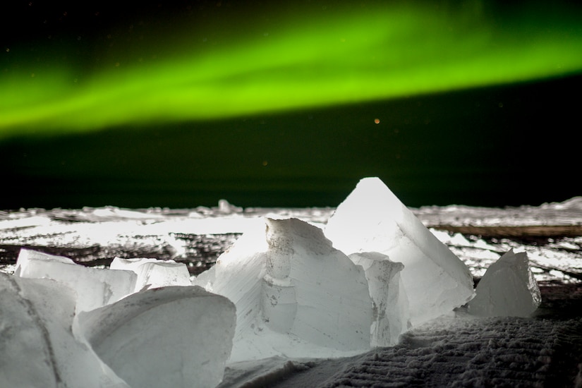 Eerie green lights streak across a dark sky.