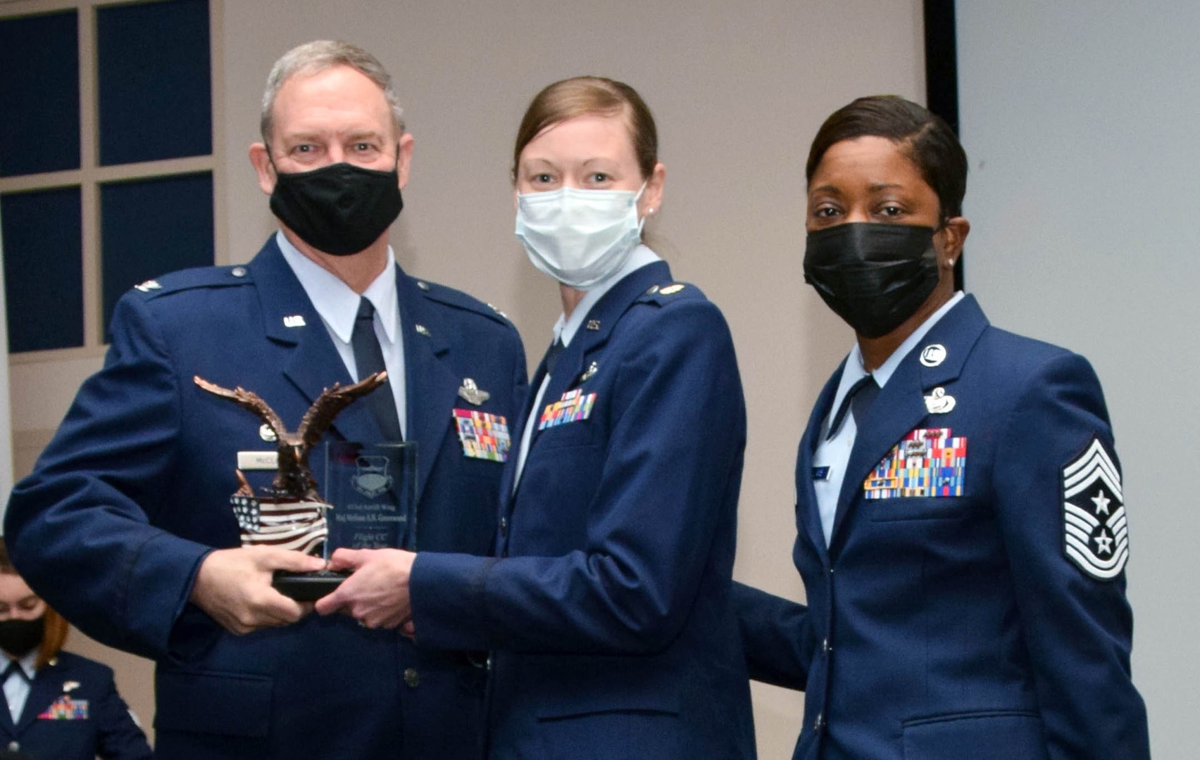 Col. Terry McClain, 433rd Airlift Wing commander, and Chief Master Sgt. Takesha Williams, 433rd AW command chief, present the Flight Commander of the Year award to Maj. Melissa Greenwood, 26th Aerial Port Squadron, at the wing’s annual awards ceremony Feb. 5, 2022, at Joint Base San Antonio-Lackland, Texas. (U.S. Air Force photo by Staff Sgt. Monet Villacorte)