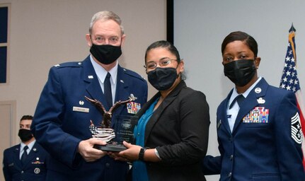 Col. Terry McClain, 433rd Airlift Wing commander, and Chief Master Sgt. Takesha Williams, 433rd AW command chief, present the Category III Civilian of the Year award to Ms. Rosario Genuardi, 433rd Logistics Readiness Squadron, at the wing’s annual awards ceremony Feb. 5, 2022, at Joint Base San Antonio-Lackland, Texas. (U.S. Air Force photo by Staff Sgt. Monet Villacorte)