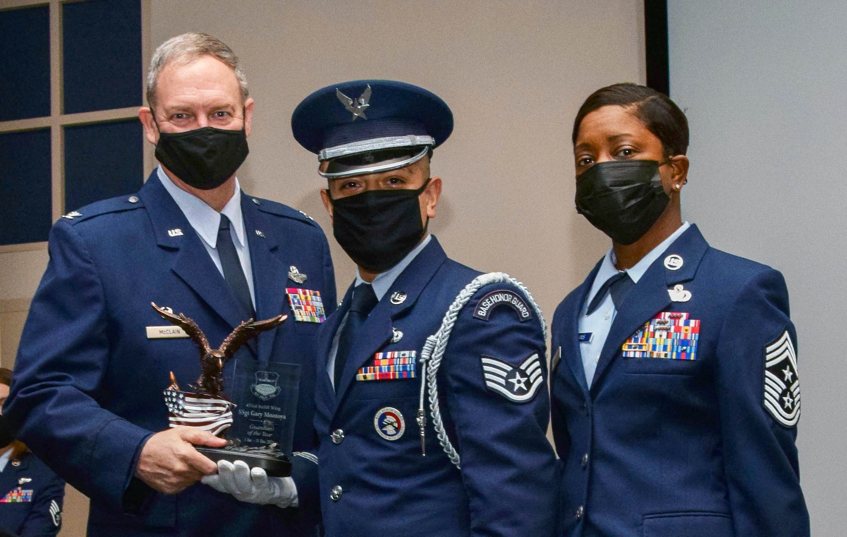 Col. Terry McClain, 433rd Airlift Wing commander, and Chief Master Sgt. Takesha Williams, 433rd AW command chief, present the Honor Guard/Guardian of the Year award to Staff Sgt. Gary Montoya, 74th Aerial Port Squadron, at the wing’s annual awards ceremony Feb. 5, 2022, at Joint Base San Antonio-Lackland, Texas. (U.S. Air Force photo by Staff Sgt. Monet Villacorte)