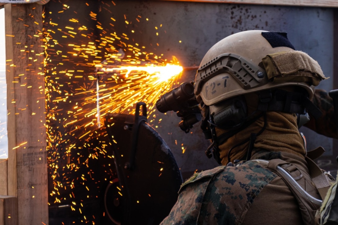 A U.S. Marine with Maritime Raid Force, 31st Marine Expeditionary Unit (MEU), cuts into a makeshift wall using a power saw aboard the USS Miguel Keith (ESB 5) to begin a Visit, Board, Search, and Seizure (VBSS) mission during operation Noble Fusion in the Philippine Sea, Feb. 5, 2022. VBSS training reinforces the Marine Corps’ presence within ocean waters by having a team at the ready to act in a moment’s notice. Noble Fusion demonstrates that Navy and Marine Corps forward-deployed stand-in naval expeditionary forces can rapidly aggregate Marine Expeditionary Unit/Amphibious Ready Group teams at sea, along with a carrier strike group, joint forces and allies in order to conduct lethal sea-denial operations, seize key maritime terrain, guarantee freedom of movement, and create advantage for US, partner and allied forces. Naval Expeditionary forces conduct training throughout the year, in the Indo-Pacific, to maintain readiness. (U.S. Marine Corps photo by Lance Cpl. Cesar Ronaldo Alarcon)