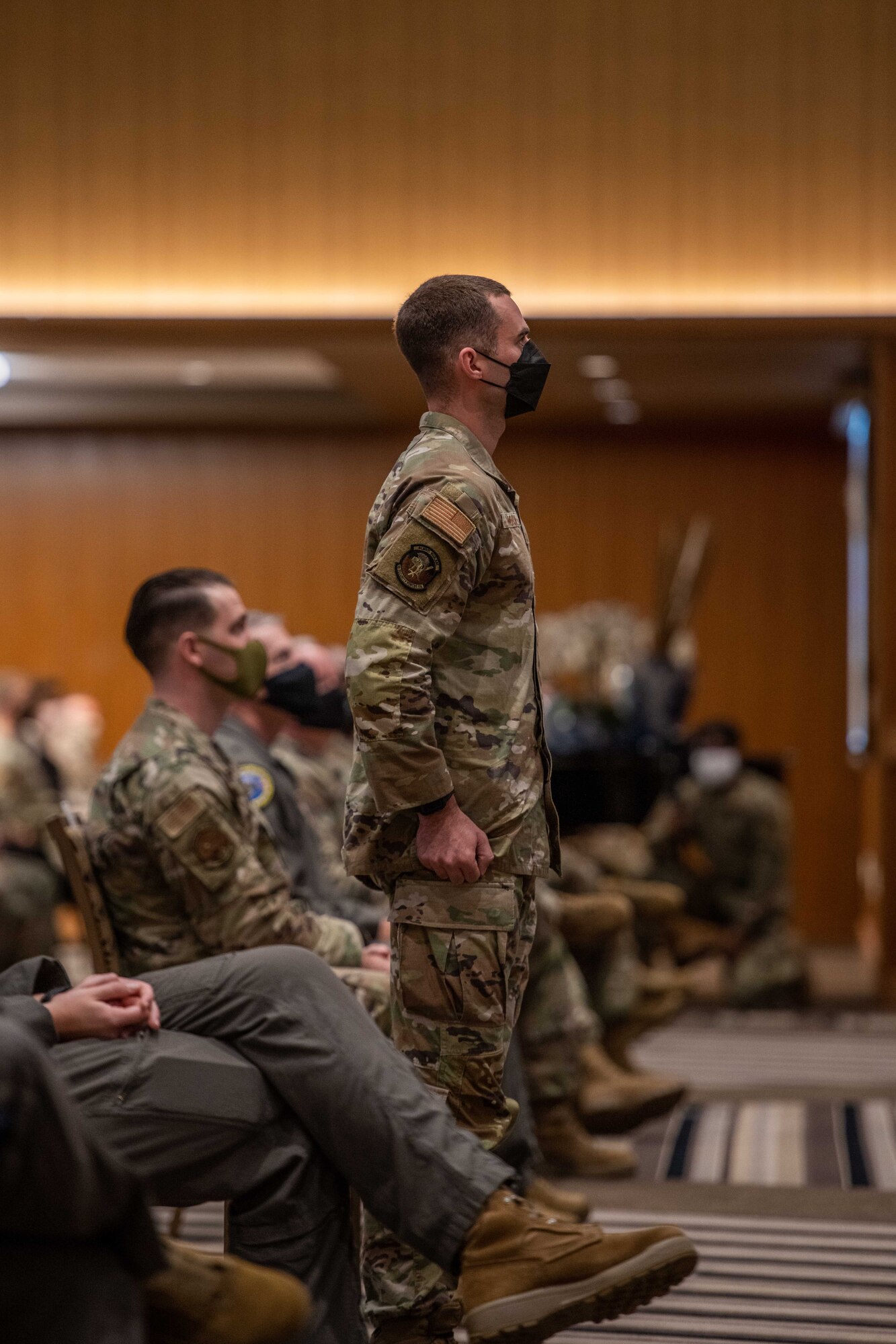 An airman stands up and is recognized during a meeting