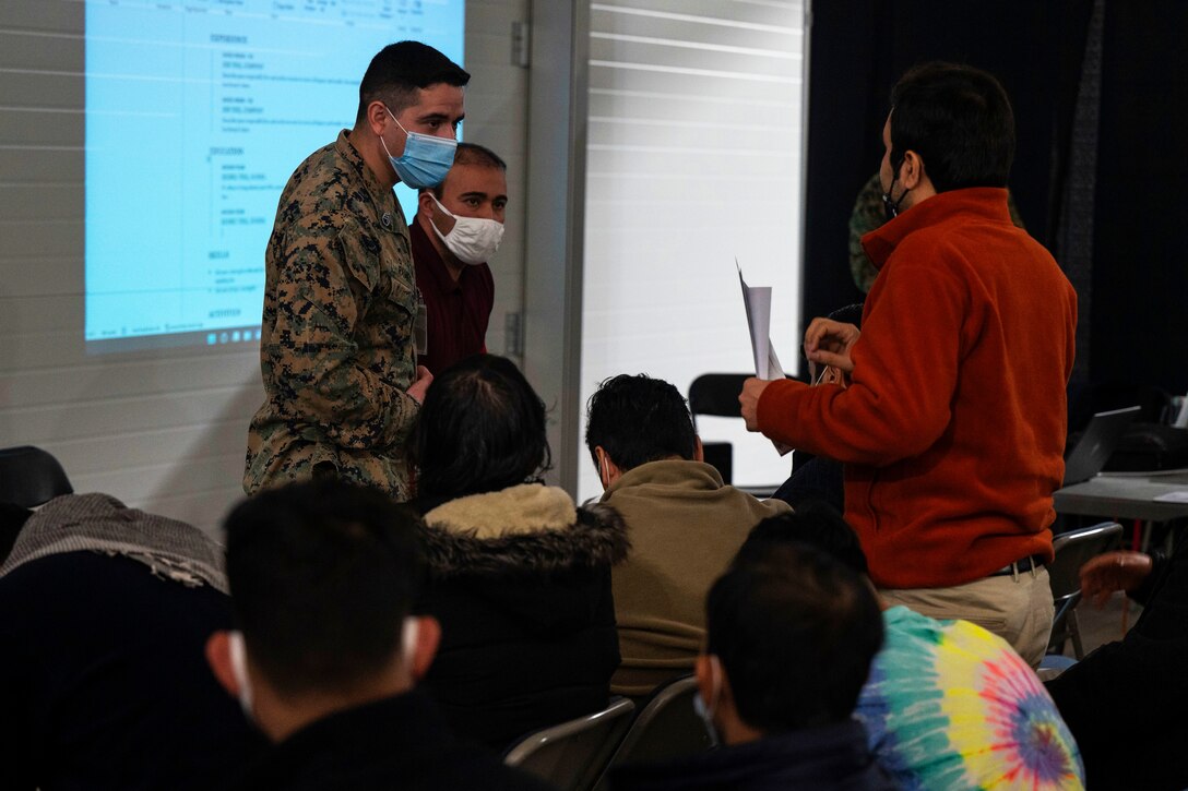 A Marine wearing a face mask listens to an Afghan guest’s question.