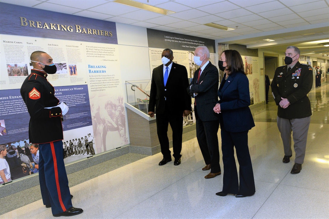 A service member talks to a group of people in a hallway.