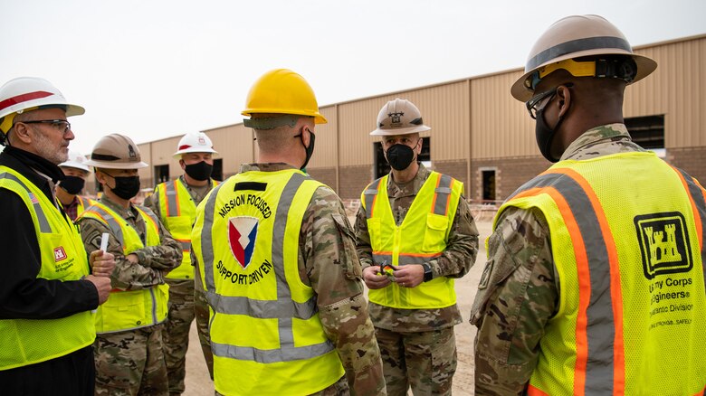 Col. Patrick McClelland (center), commander of Army Materiel Command's 401st Army Field Support Brigade,, briefs Lt. Gen. Scott A. Spellmon, the 55th Chief of Engineers and commanding general of U.S. Army Corps of Engineers, on the construction of an APS-500 building, located at Camp Arifjan, Kuwait, on Jan. 31, 2022. When completed the facility will provide critical environmental protection for Army Materiel Command's pre-positioned stock, part of a U.S. Army program in which equipment sets are stored around the globe for use when a combatant commander requires additional