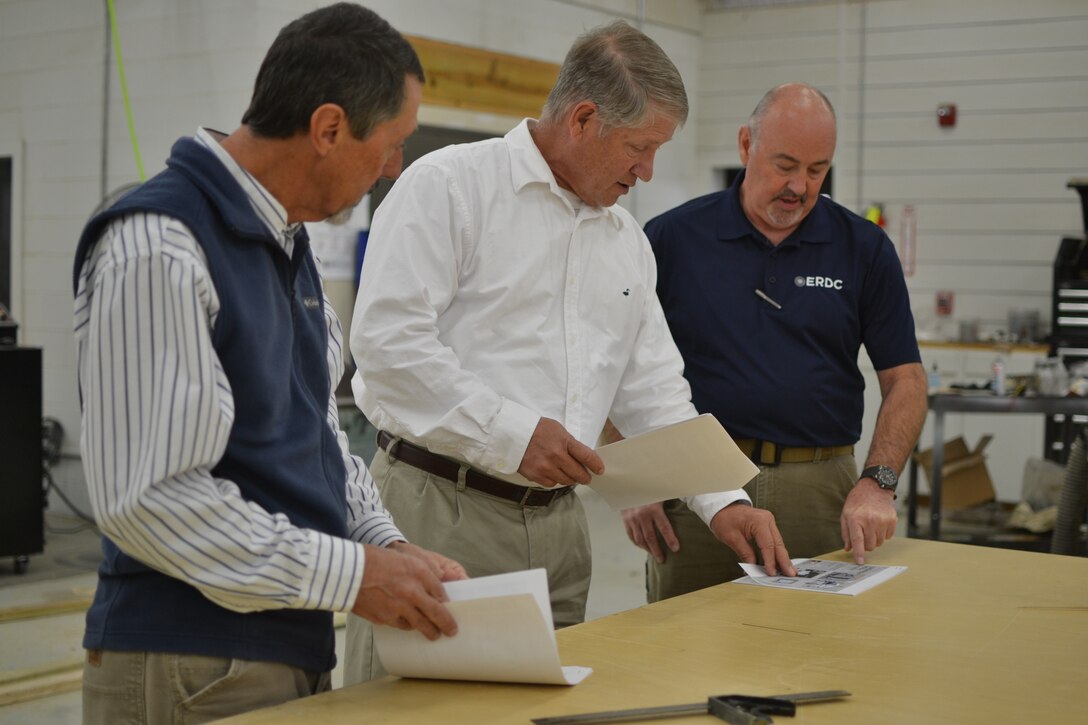 David Rogillio, Michael Channell and Mickey Blackmon of the U.S. Army Engineer Research and Development Center (ERDC) review plans for containerized medical solutions, a quickly assembled, low-cost method of building airborne infectious isolation rooms using commercially available intermodal container units. 
In addition to the ERDC personnel, the invention team also included U.S. Army Engineering and Support Center's David Braidich of Manassas, Virginia; Brian Roden of Madison, Alabama; and Bryan Merry of Huntsville, Alabama.