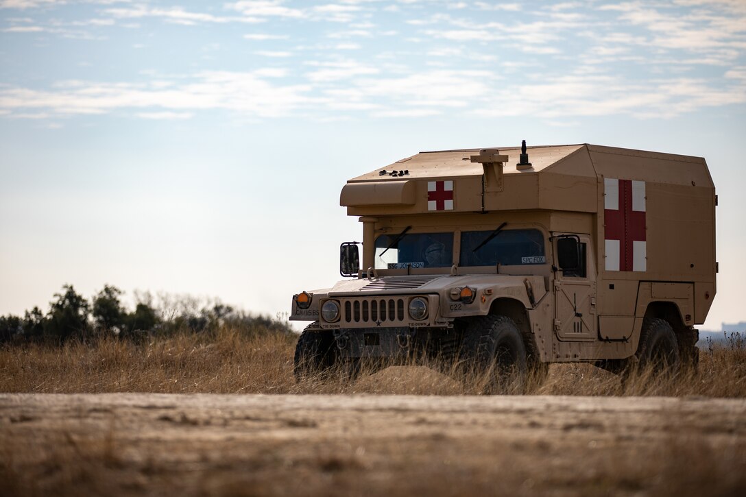 A military ambulance sits in a field.