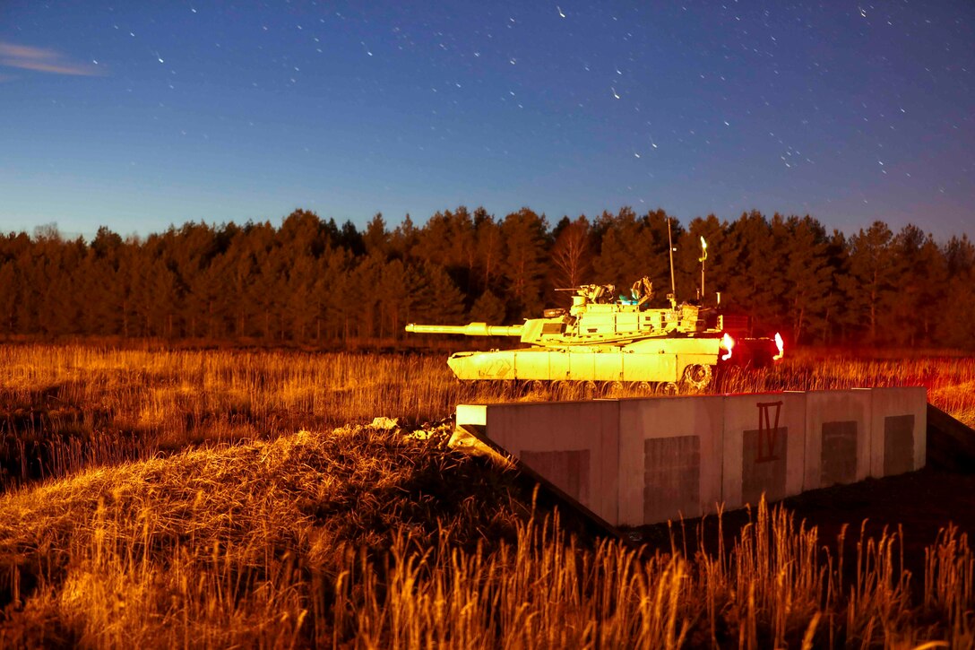 A tank in a grassy field at night.