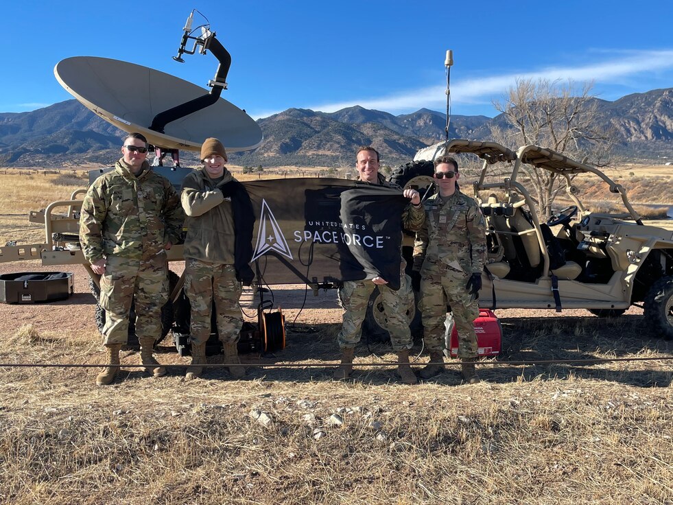 members of space delta 3 stand in front of the new MACE antenna holding a space force flag.