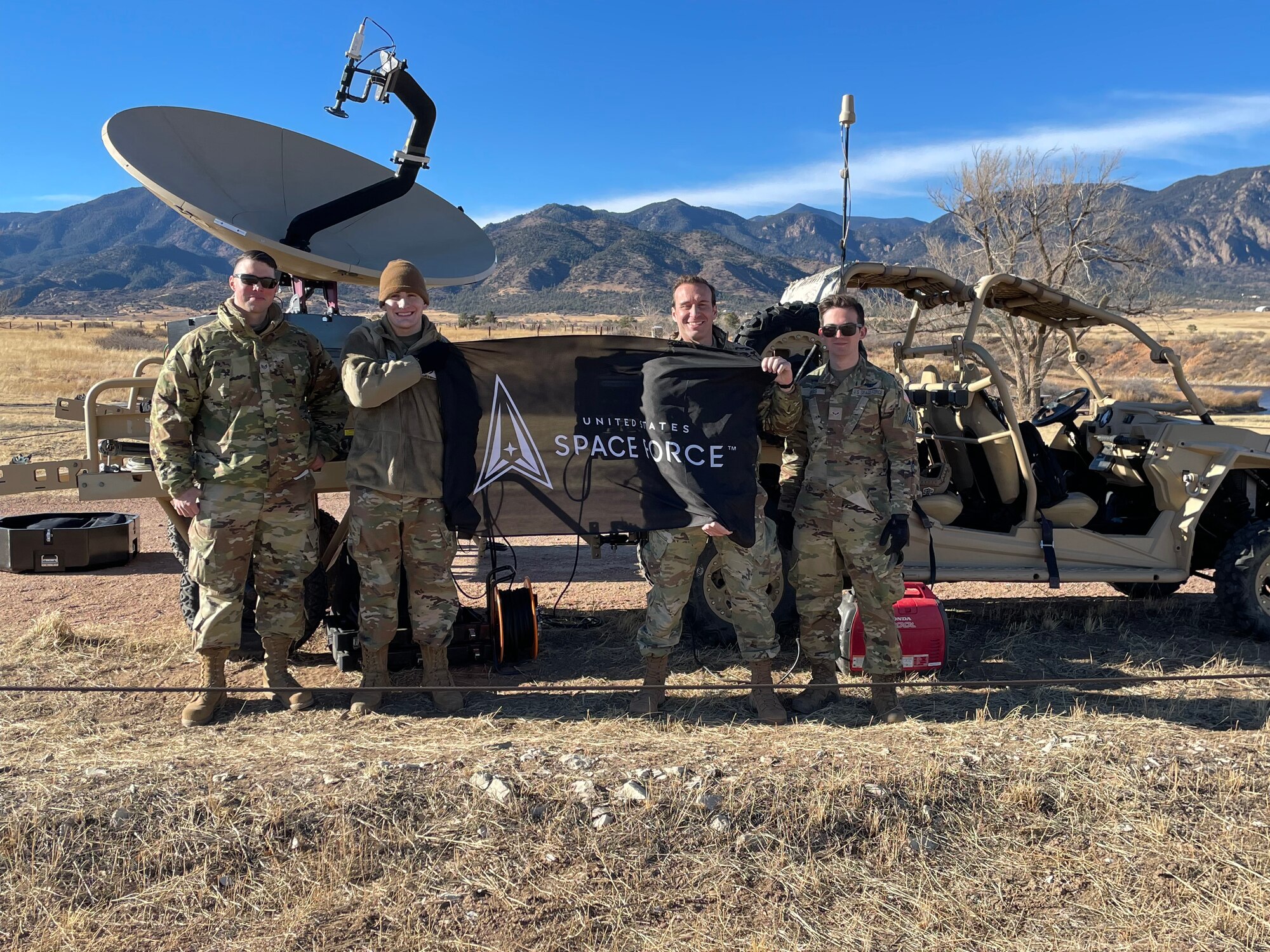 members of space delta 3 stand in front of the new MACE antenna holding a space force flag.