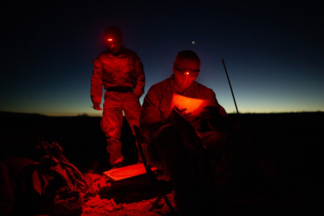 Two Marines use headlamps at night.