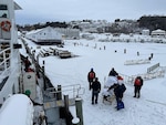 Crewmembers from Coast Guard Cutter Katmai Bay and emergency workers embark a patient being medevaced from Mackinac Island, Mich. February 7, 2022. The ship diverted from its icebreaking mission on the St. Marys RIver to take on the case. U.S. Coast Guard photo.