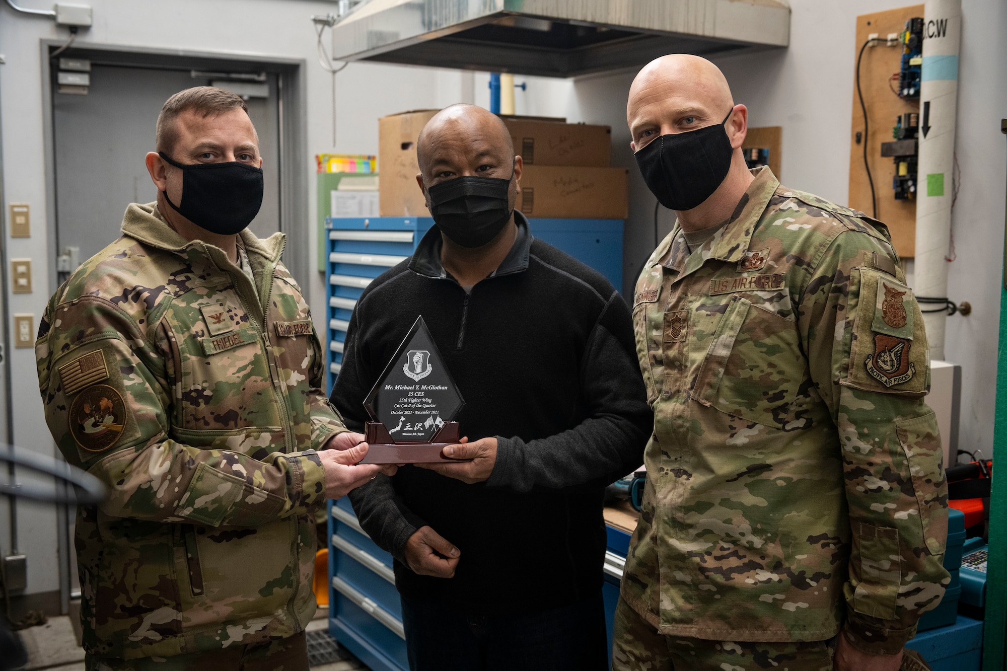 Group of military member in uniform present an award to civilian.