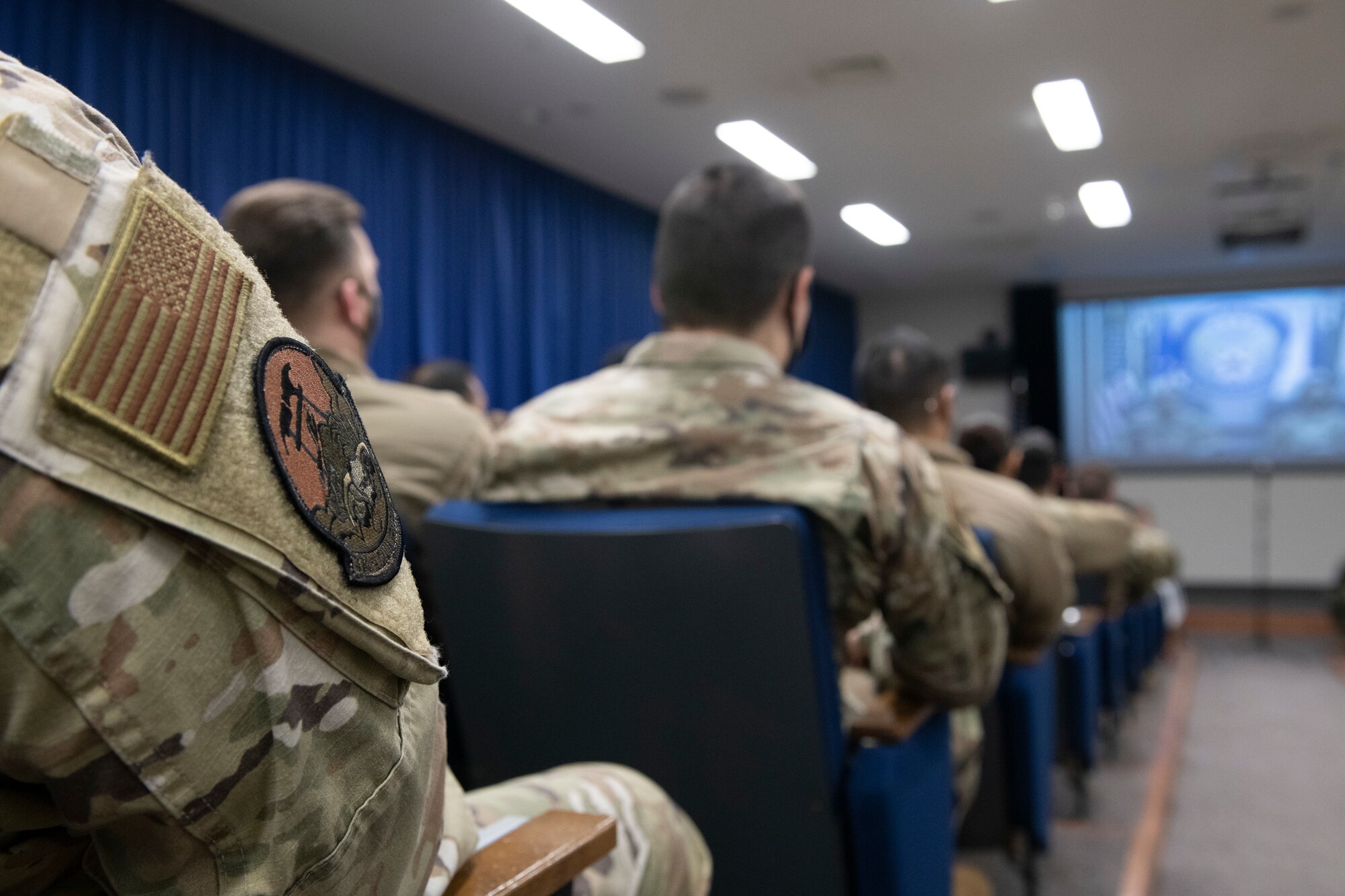 Members of the 374th Mission Support Group watch a virtual all-call with Air Force Chief of Staff Gen. CQ Brown, Jr., and Chief Master Sgt. of the Air Force JoAnne S. Bass Feb. 8, 2022, at Yokota Air Base, Japan. Brown and Bass answered Airmen’s questions on mentoring, the Exceptional Family Member Policy, and inflation. (U.S. Air Force photo by Tech. Sgt. Joshua Edwards)