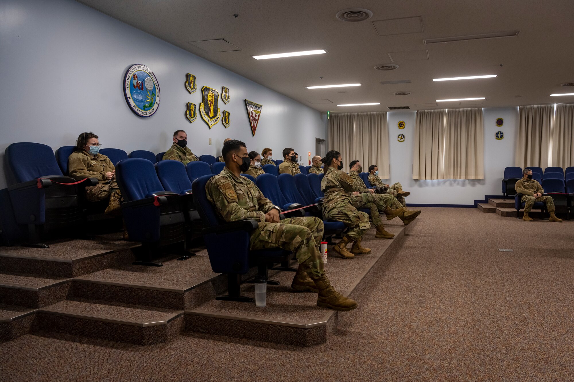 Airmen in a conference room listening to a virtual call.