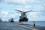 PHILIPPINE SEA (Feb. 6, 2022) Aviation Boatswain’s Mate (Handling) 3rd Class Shelby Mann, from Udall, Kan., assigned to the forward-deployed amphibious assault ship USS America (LHA 6), signals a CH-47J Chinook helicopter from the Japan Ground Self-Defense Force to take off from the ship’s flight deck during Exercise Noble Fusion. Noble Fusion demonstrates that Navy and Marine Corps forward-deployed stand-in naval expeditionary forces can rapidly aggregate Marine Expeditionary Unit/Amphibious Ready Group teams at sea, along with a carrier strike group, as well as other joint force elements and allies, in order to conduct lethal sea-denial operations, seize key maritime terrain, guarantee freedom of movement, and create advantage for U.S., partner and allied forces. Naval Expeditionary forces conduct training throughout the year, in the Indo-Pacific, to maintain readiness. (U.S. Navy photo by Mass Communication Specialist 2nd Class Vincent E. Zline)