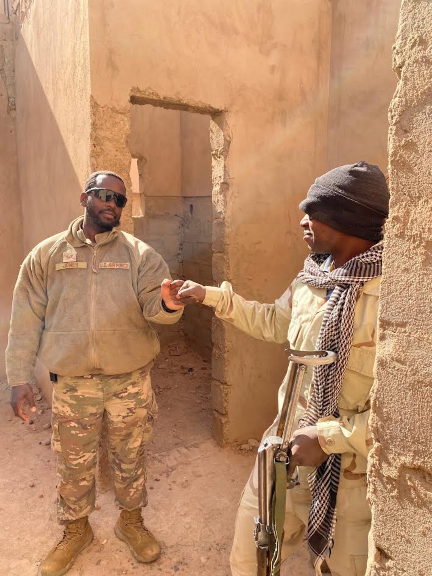 Senior Airmen Jamille Jones, 409th Expeditionary Security Forces Squadron air advisors, fist-pumps a Nigerien Armed Forces (French language: Forces Armées Nigeriennes) members at the end of a close-quarters battle scenario at Nigerien Air Base 201, Agadez, Niger, Feb. 3, 2022. Developing African partner capability while countering violent extremism helps build regional self-reliance and impedes detrimental influences on the continent.  (U.S. Air Force courtesy photo by Capt. Brian Tabares)