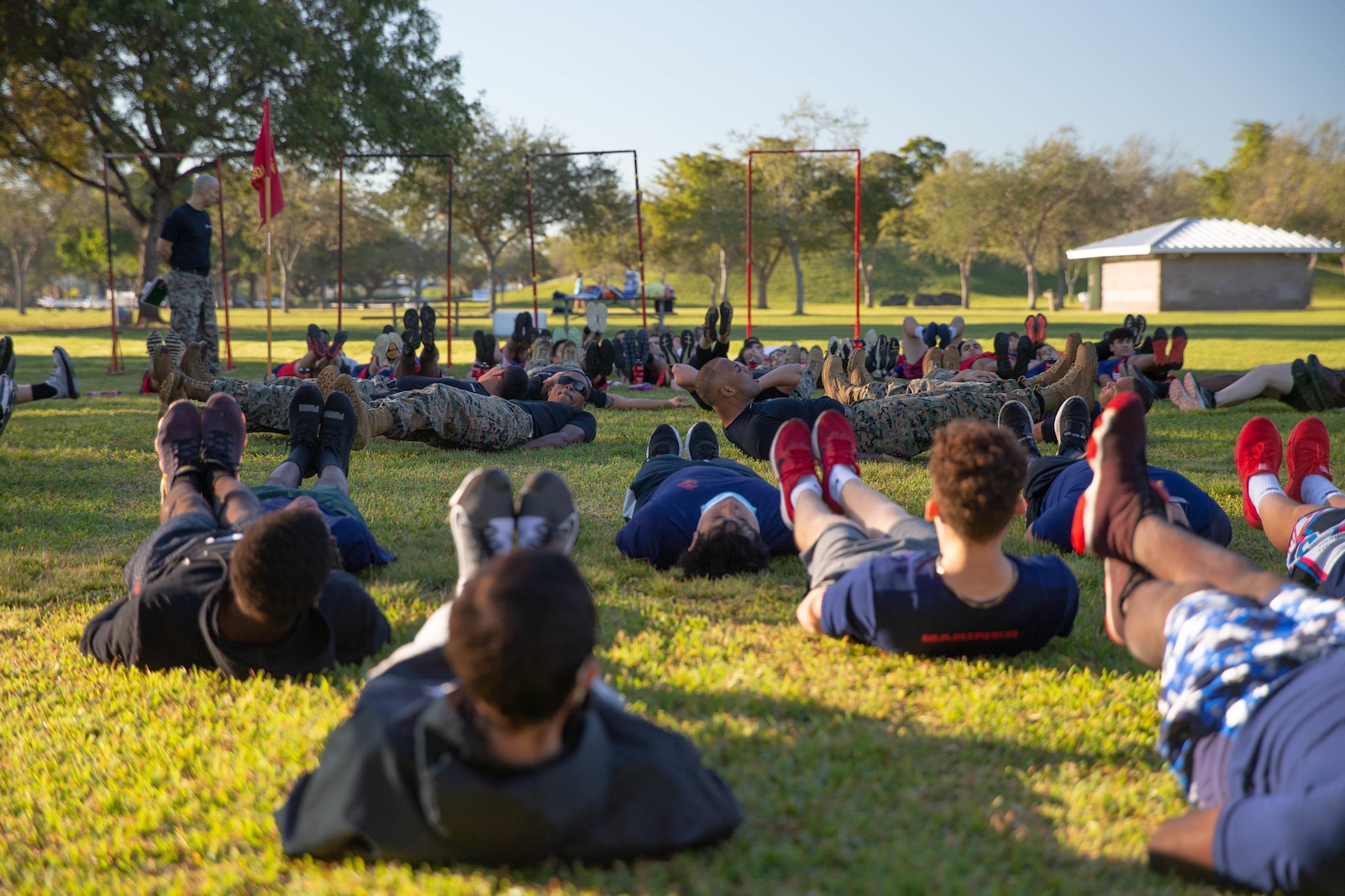 U.S. Marine Corps recruiters conduct leg raises as part of the warm up portion of a field meet held in Miami, Florida, Jan. 15, 2022. Recruiting substations Hialeah, Miami, Perrine and South Dade faced each other in a friendly competition during a field meet for the title of "Recruiting Station Fort Lauderdale South Field Meet Champion". (U.S. Marine Corps photo by Lance Cpl. Kevin Lopez Herrera)