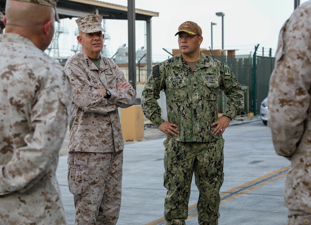 NAVAL SUPPORT ACTIVITY, BAHRAIN (Dec. 16, 2021) Gen. David H. Berger, 38th Commandant of the Marine Corps, left, and Cmdr. Thomas Mcandrew, talks to each other in front of a Task Force 59 (TF 59) display at Naval Support Activity, Bahrain, Dec 16. TF 59 is the first U.S. Navy task force of its kind, designed to rapidly integrate unmanned systems and artificial intelligence with maritime operations in the U.S. 5th Fleet area of operations (U.S. Army photo by Cpl Deandre Dawkins)