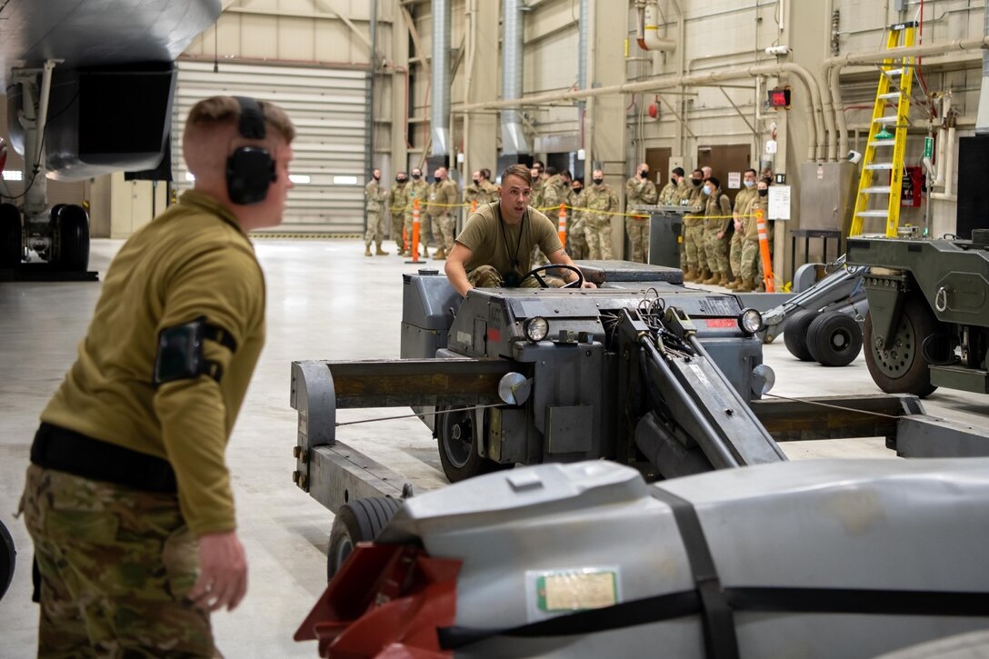 Staff Sgt. Cody Wagner, 28th Maintenance Group weapons load crew chief, guides Airman 1st Class AJ Barkalow, 28th Maintenance Group load crew member, using a munitions handling truck to lift an AGM-158 Joint Air-to-Surface Standoff Missile during a Maintenance Group quarterly load competition on Ellsworth Air Force Base, S.D., Jan. 28, 2022.