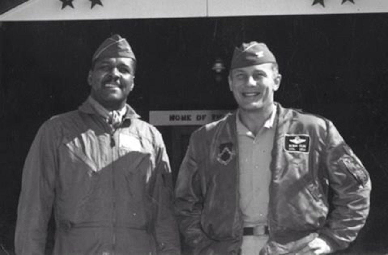 Two men stand smiling beside each other.