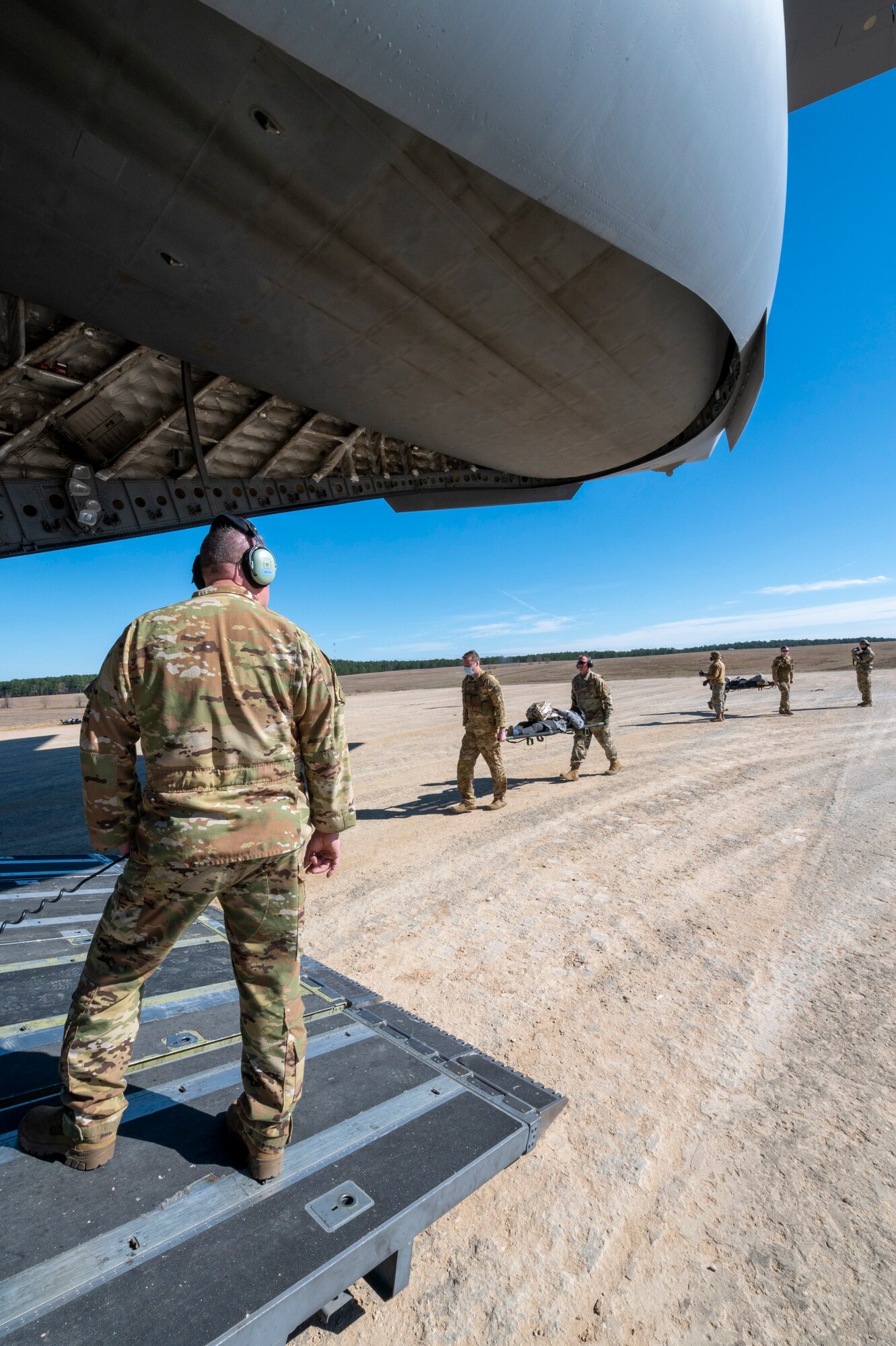 U.S. Air Force Chief Master Sgt. Mark Synder, a loadmaster with the 167th Airlift Squadron, waits for patients to be loaded by aeromedical evacuation specialists during exercise Green Flag Little Rock 22-03 at Ft. Polk, Louisiana, Jan. 13, 2022. GFLR 22-03 focused on three joint-accredited items: combat airlift; survival, evasion, resistance and escape; and aeromedical evacuation.