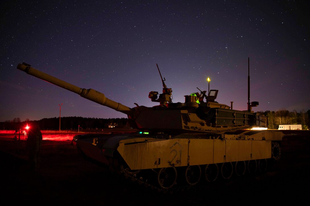 A tank at night with red and yellow light under a starry sky.