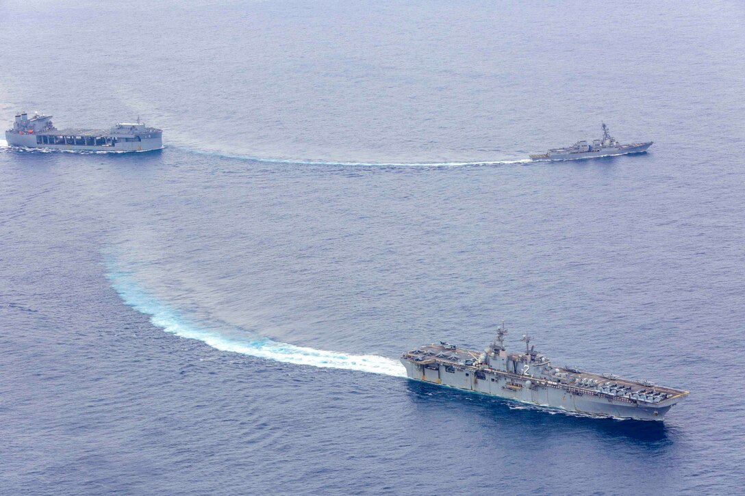 Three ships travel through waters.