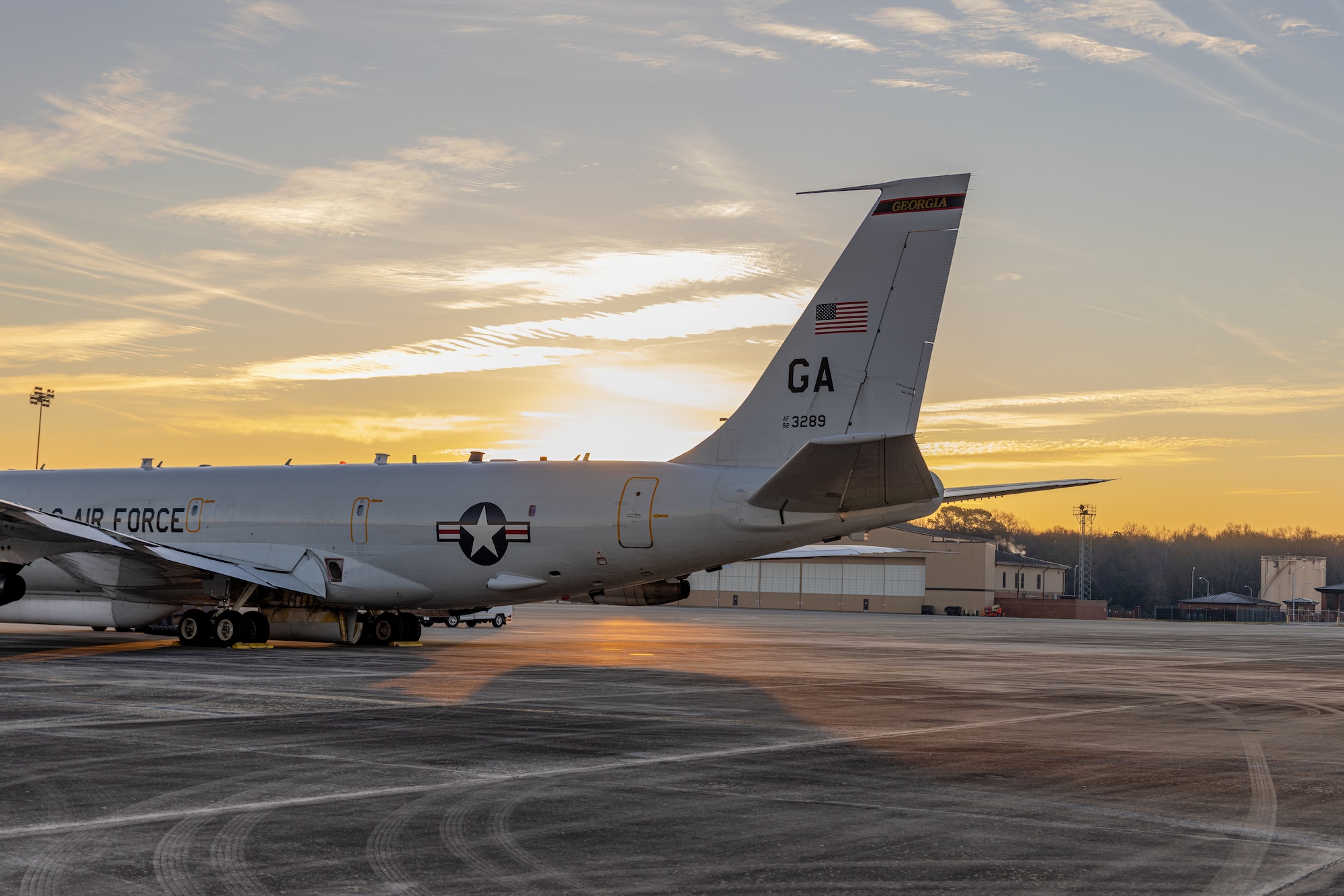 Photo shows a plane's tail with the sun rising behind it.