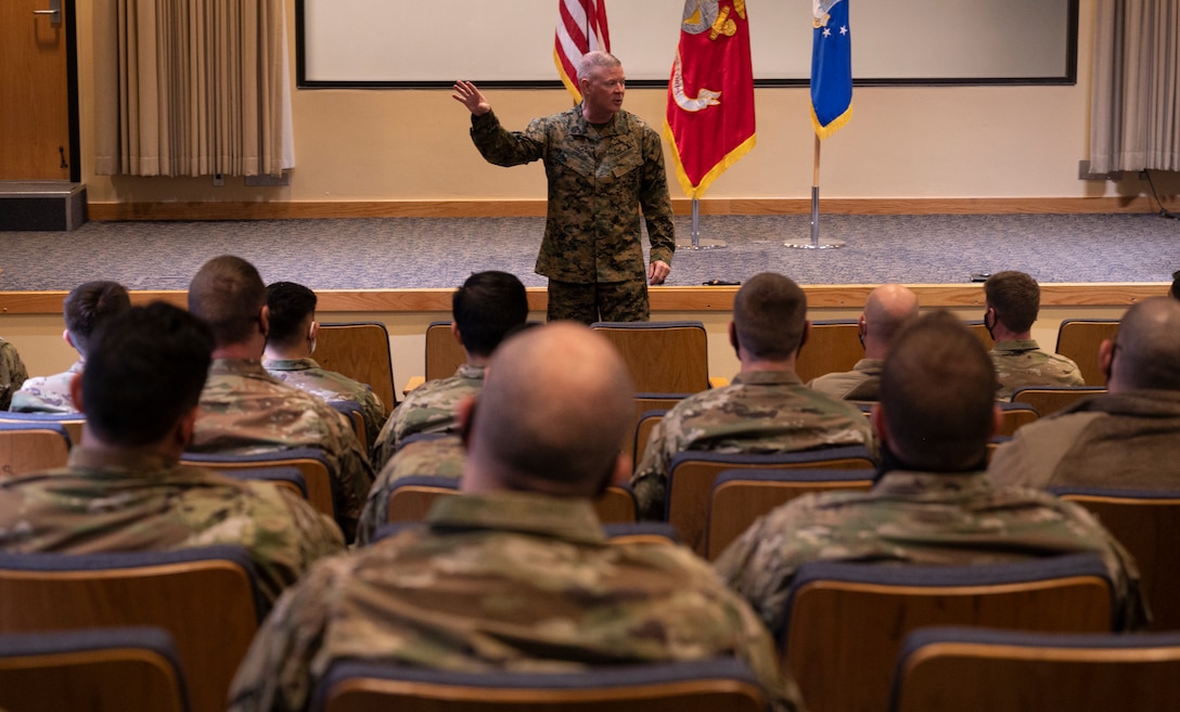 A man stands in an auditorium speaking to a seated crowd.