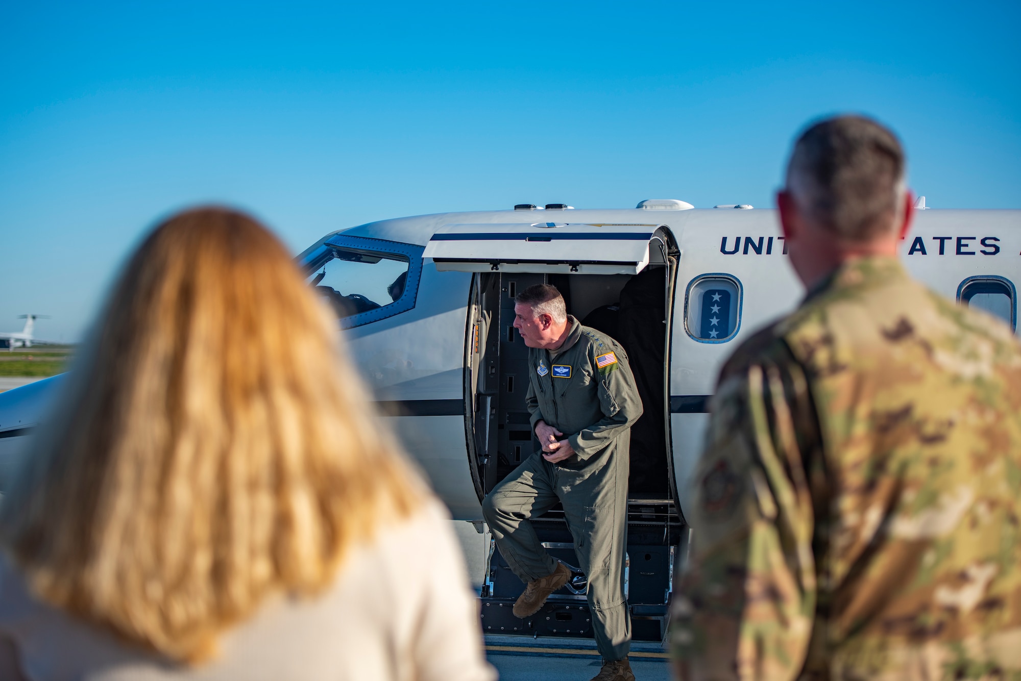 A man gets out of a plane and is greeted by others