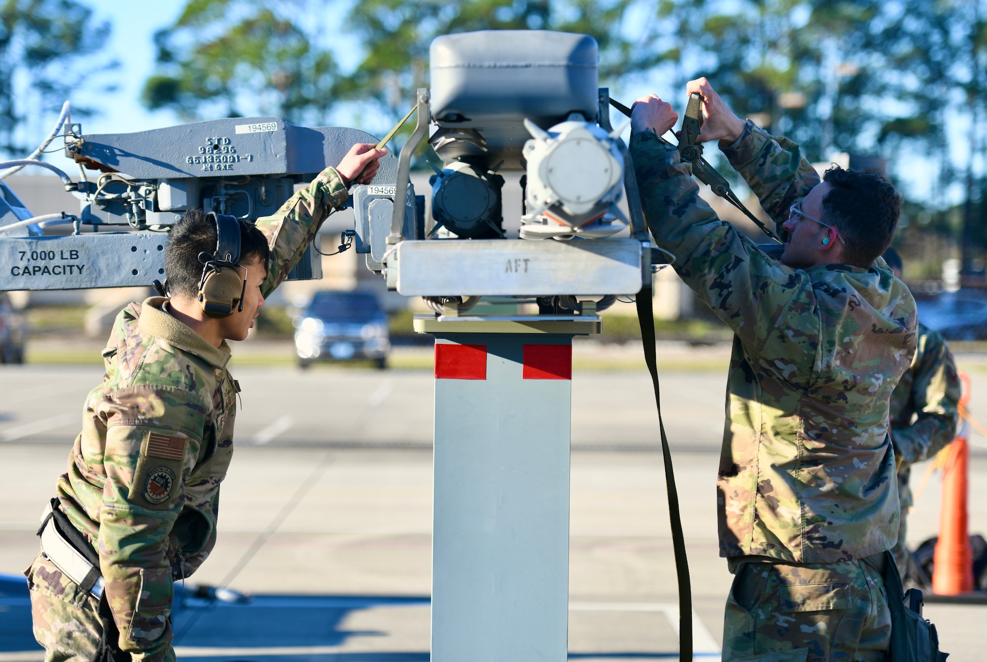 U.S. Air Force Senior Airman Kaipoalohiolamahinap Fukumoto (left) and Staff Sgt. Mark Carrico, 73rd Aircraft Maintenance Unit weapons load crew members, secure a trainer BRU-61 bomb prior to lifting it off of its storage rack during the 1st Special Operations Wing’s Weapons Load Crew of the 4th Quarter Competition Jan. 7, 2022 on the flightline at Hurlburt Field, Florida.