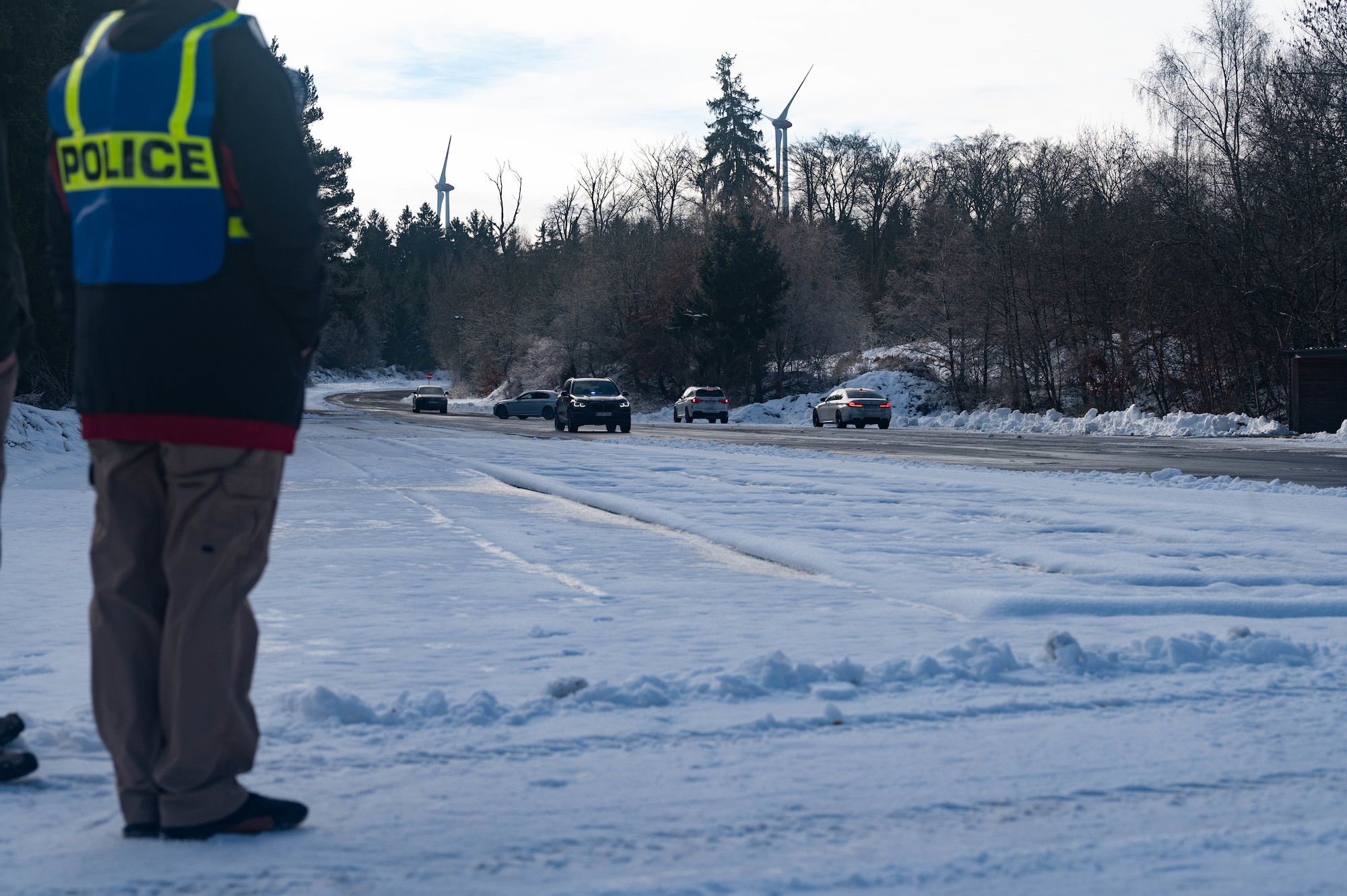 A person standing with vehicles driving in the distance.