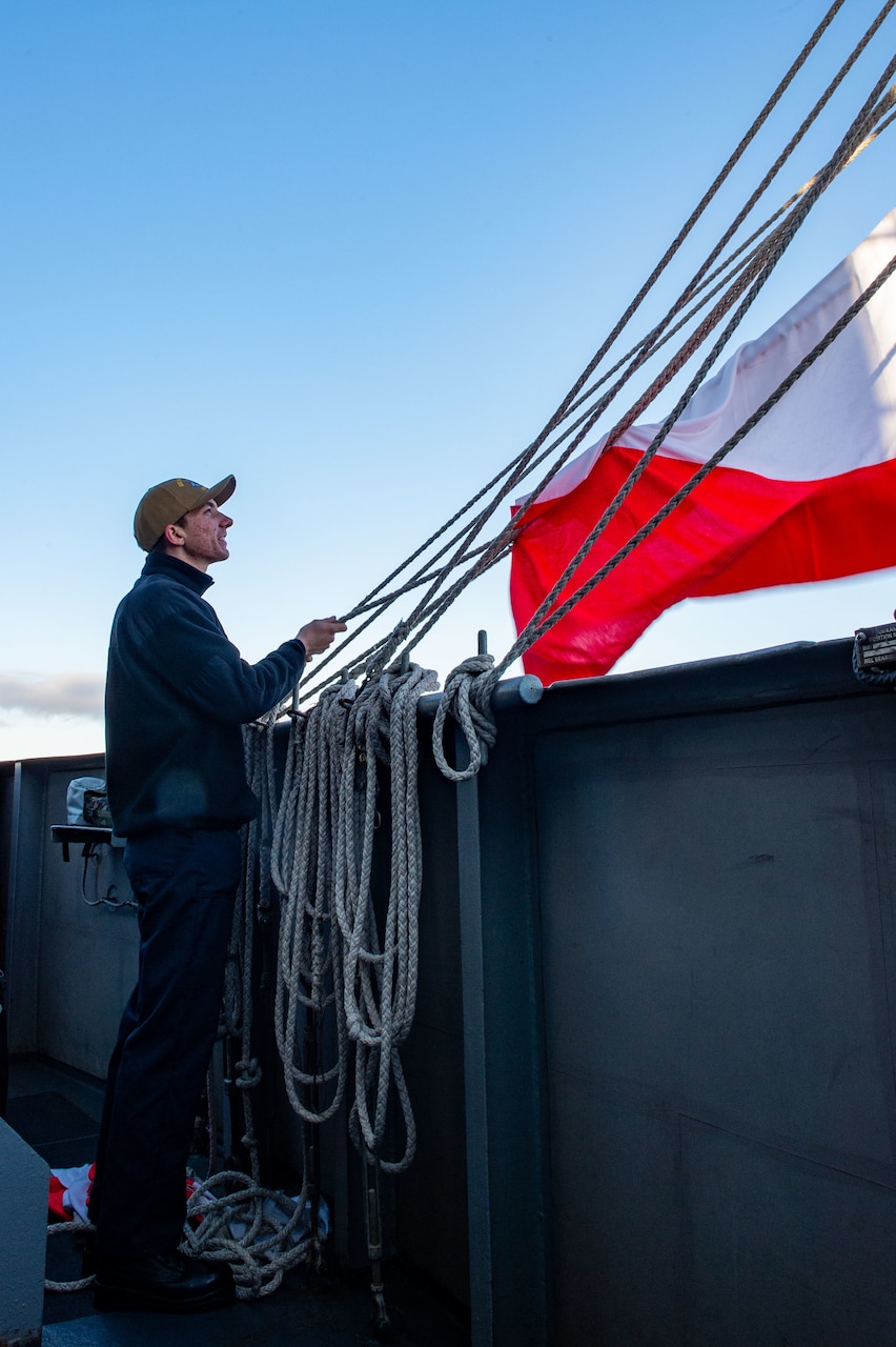 Quartermaster Seaman Matthew Braswell, from Tampa, Florida, hoists the hotel flag on the Nimitz-class aircraft carrier USS Harry S. Truman (CVN 75), Feb. 11, 2022.