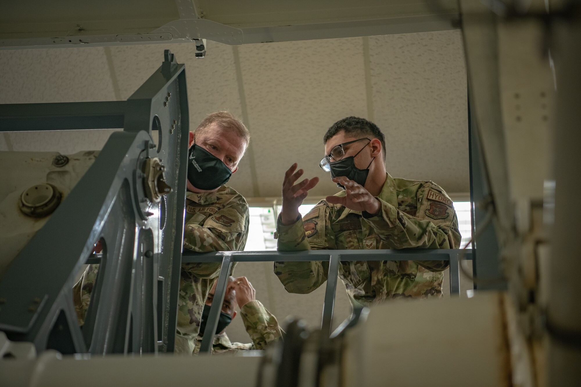 Senior Airman Jordan Hughes, 349th Maintenance Squadron, briefs Lt. Gen. Richard W. Scobee, chief of the Air Force Reserve and commander of the Air Force Reserve Command, on the mechanics of their landing gear training simulator at Travis Air Force Base, California, Feb. 12, 2022. Scobee and his senior enlisted advisor visited the 349th Air Mobility Wing to learn more about its people, mission, accomplishments, and innovation efforts.
