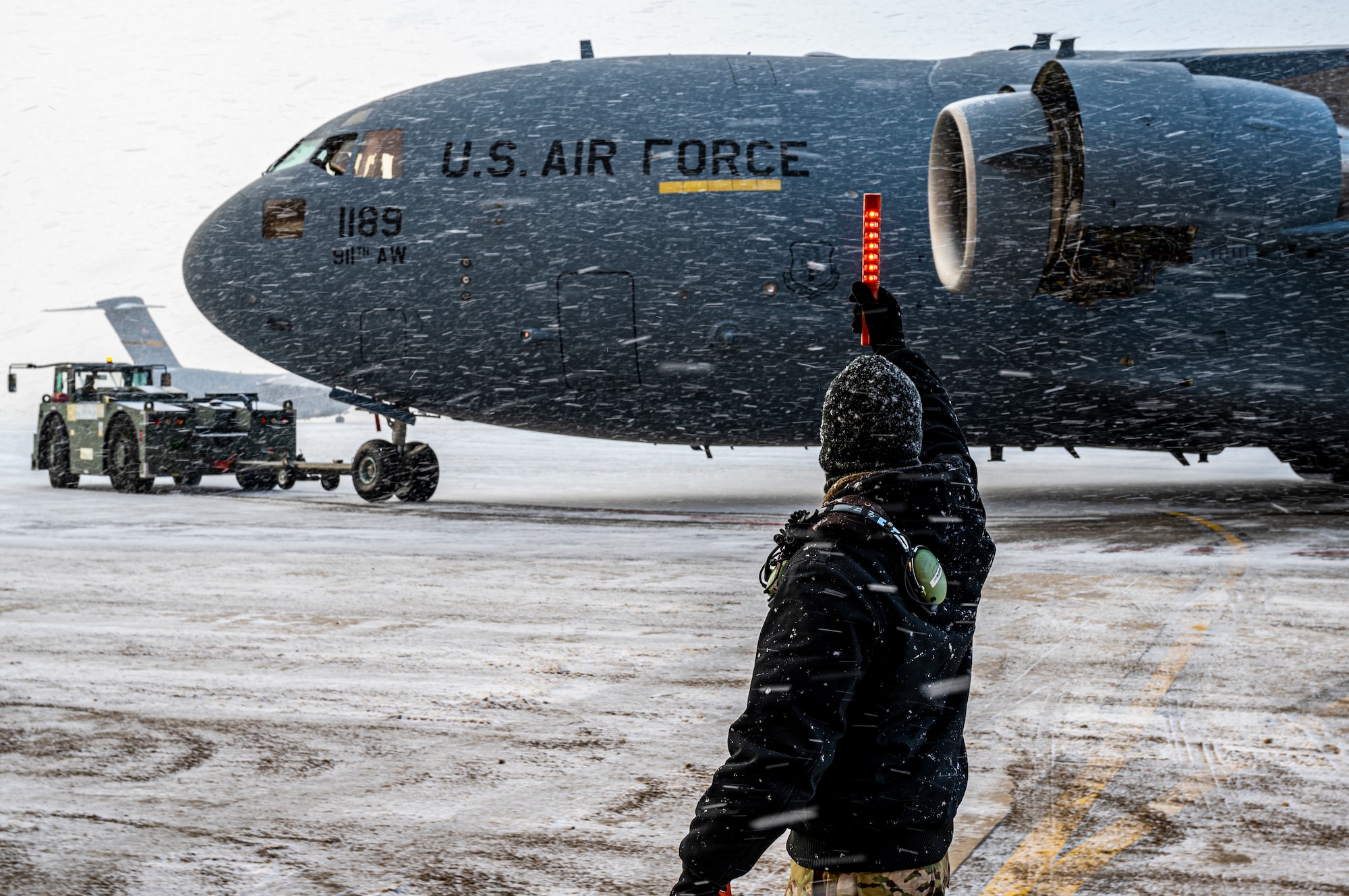 Tech. Sgt. Jeffrey Raymond, 911th Maintenance Squadron crew chief, relays information to the tow team supervisor while towing a C-17 Globemaster III aircraft from the two-bay hangar onto the flight line at the Pittsburgh International Airport Air Reserve Station, Pennsylvania, Jan. 20, 2022.