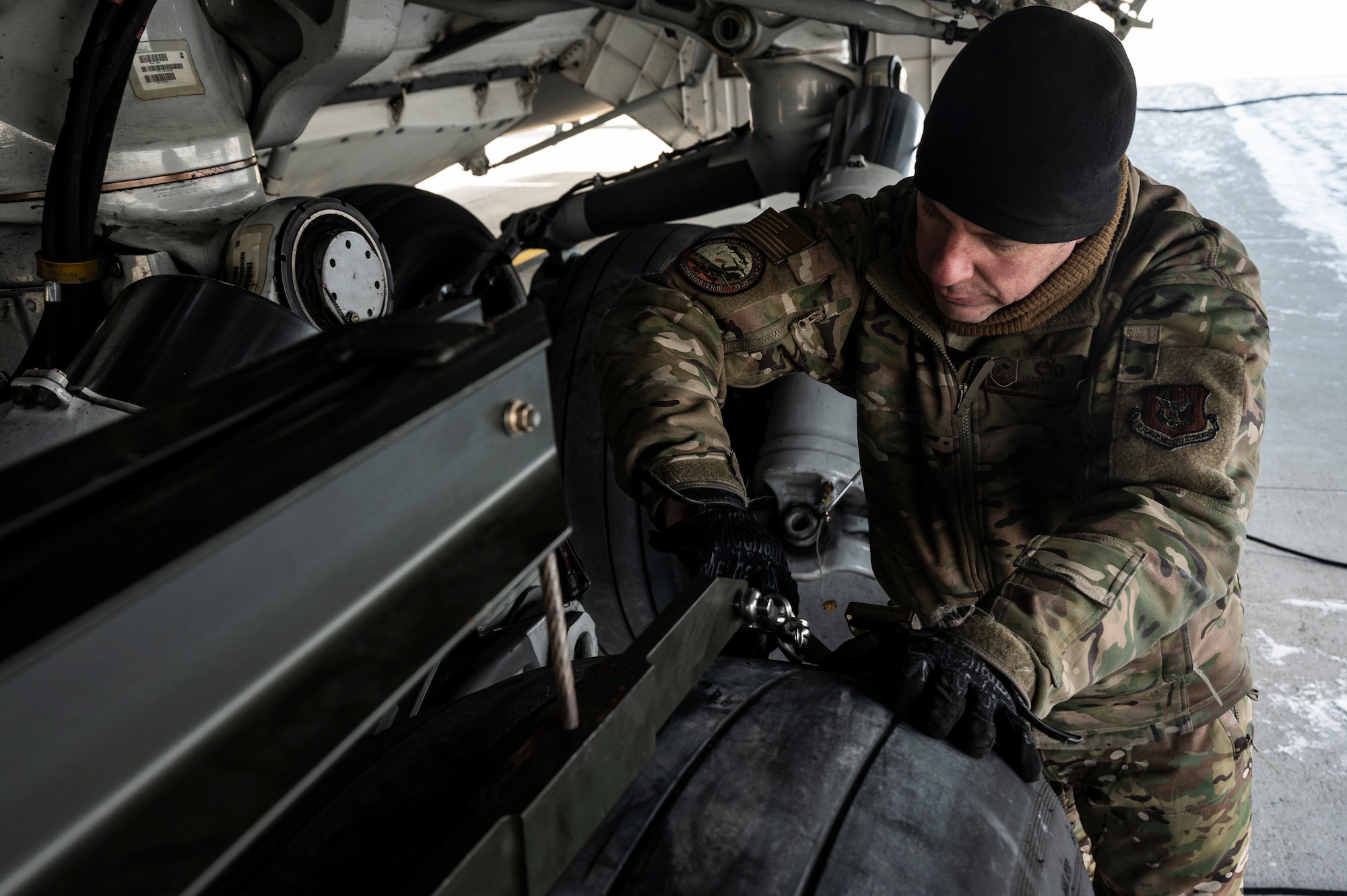 Master Sgt. Jason Hlavsa, 911th Aircraft Maintenance Squadron crew chief, connects a harness around a C-17 Globemaster III tire while preparing to change the tire at the Pittsburgh International Airport Air Reserve Station, Pennsylvania, Jan. 11, 2022.