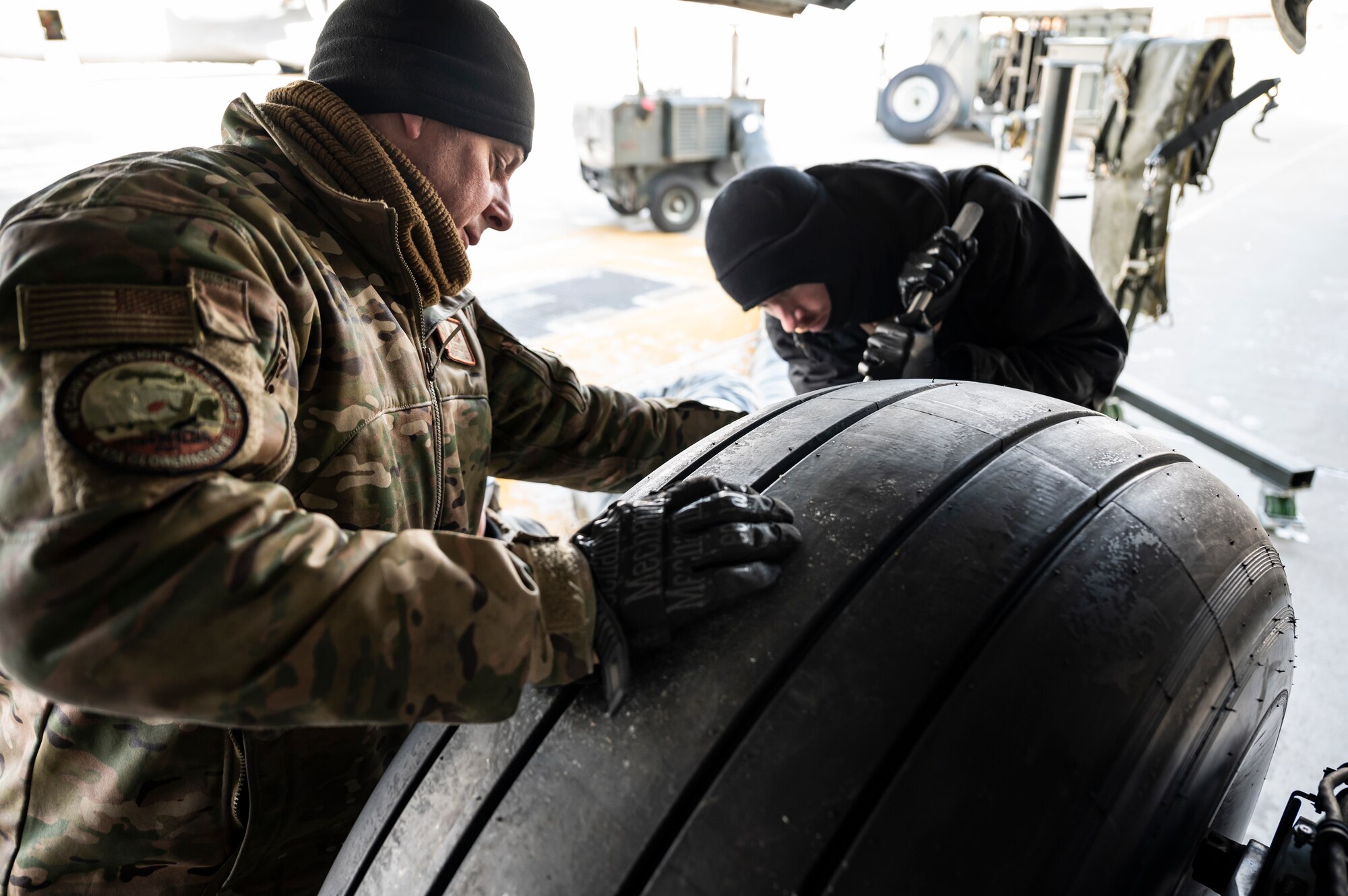 Master Sgt. Jason Hlavsa, and Master Sgt. John Thompson, 911th Aircraft Maintenance Squadron crew chiefs, tighten a bolt while changing a tire on a C-17 Globemaster III at the Pittsburgh International Airport Air Reserve Station, Pennsylvania, Jan. 11, 2022.