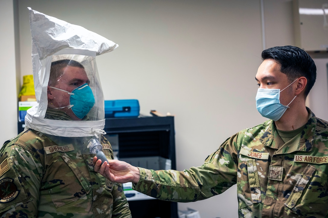 An airman wearing a face mask conducts an N95 mask fit test on another airman.