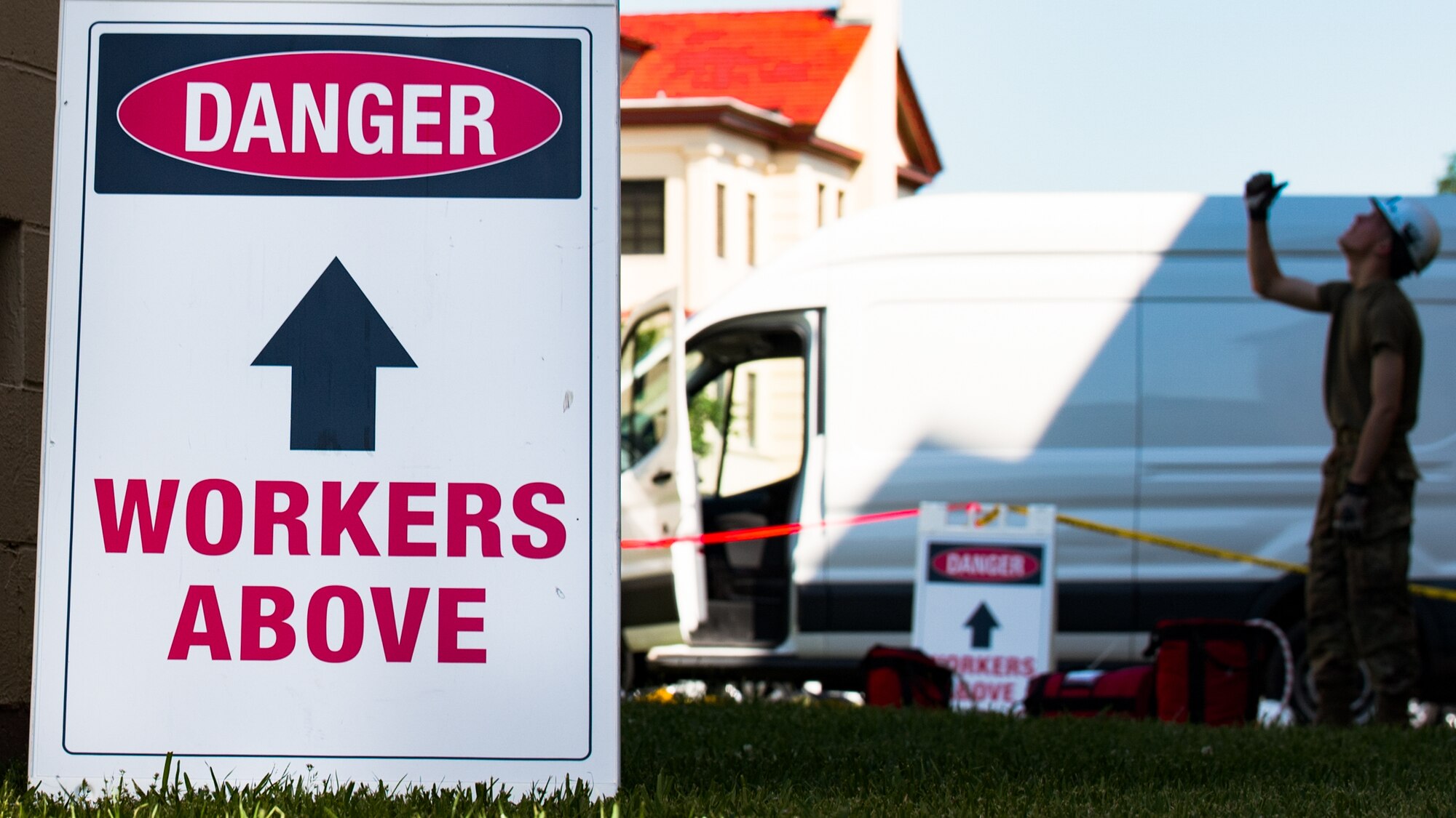 sign with text danger workers above. Person with helmet on looking up.
