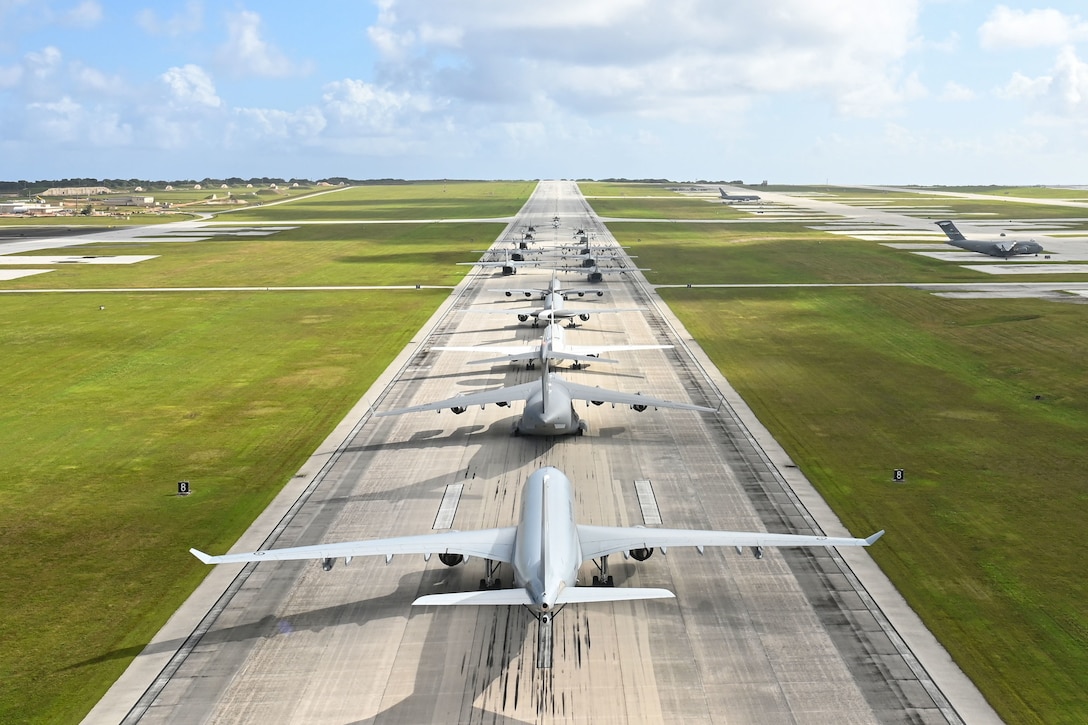 Military aircraft line up on a runway.