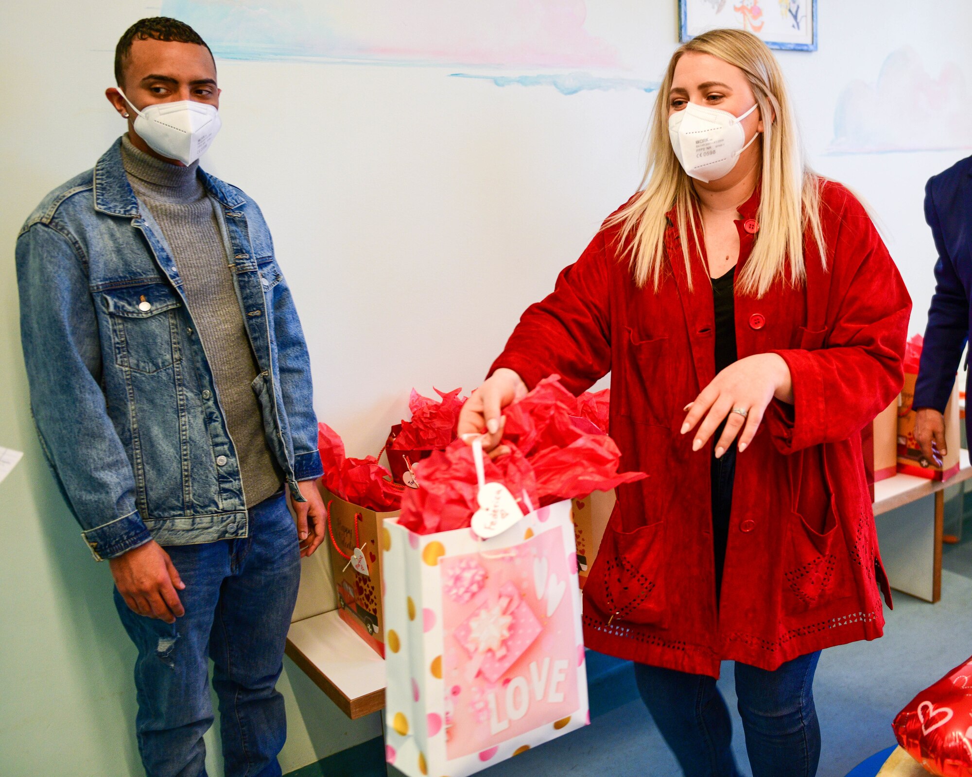 Senior Airman Nelson Roman, 31st Security Forces Squadron Pass & Registration clerk, left, and U.S. Air Force Staff Sgt. Hannah Hannas, 31st SFS Pass & Reg assistant noncommissioned officer in charge, give gift bags to children in the pediatric oncology ward of the Pordenone Hospital in Pordenone, Italy, Feb. 14, 2022. Due to COVID-19, the donations were given to the children in the lobby area. The gift bags were delivered to children ages 9 months to 15 years old and each gift bag was tailored to the age of the child. (U.S. Air Force photo by Senior Airman Brooke Moeder)