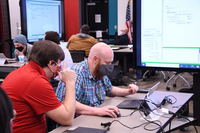 IMAGE: Naval Surface Warfare Center Dahlgren Division Force Analyst Josh Shiben assists the team from the Electromagnetic and Sensor Systems Department. All seven of NSWCDD’s technical departments participated in the hackathon.