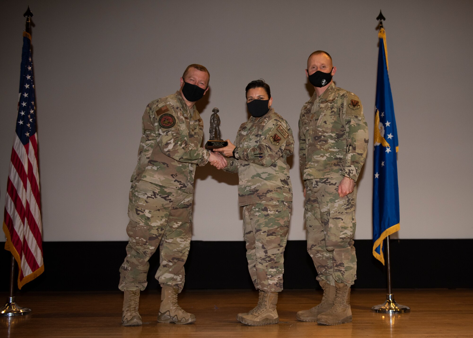 Three Airmen pose for a photo with a trophy.