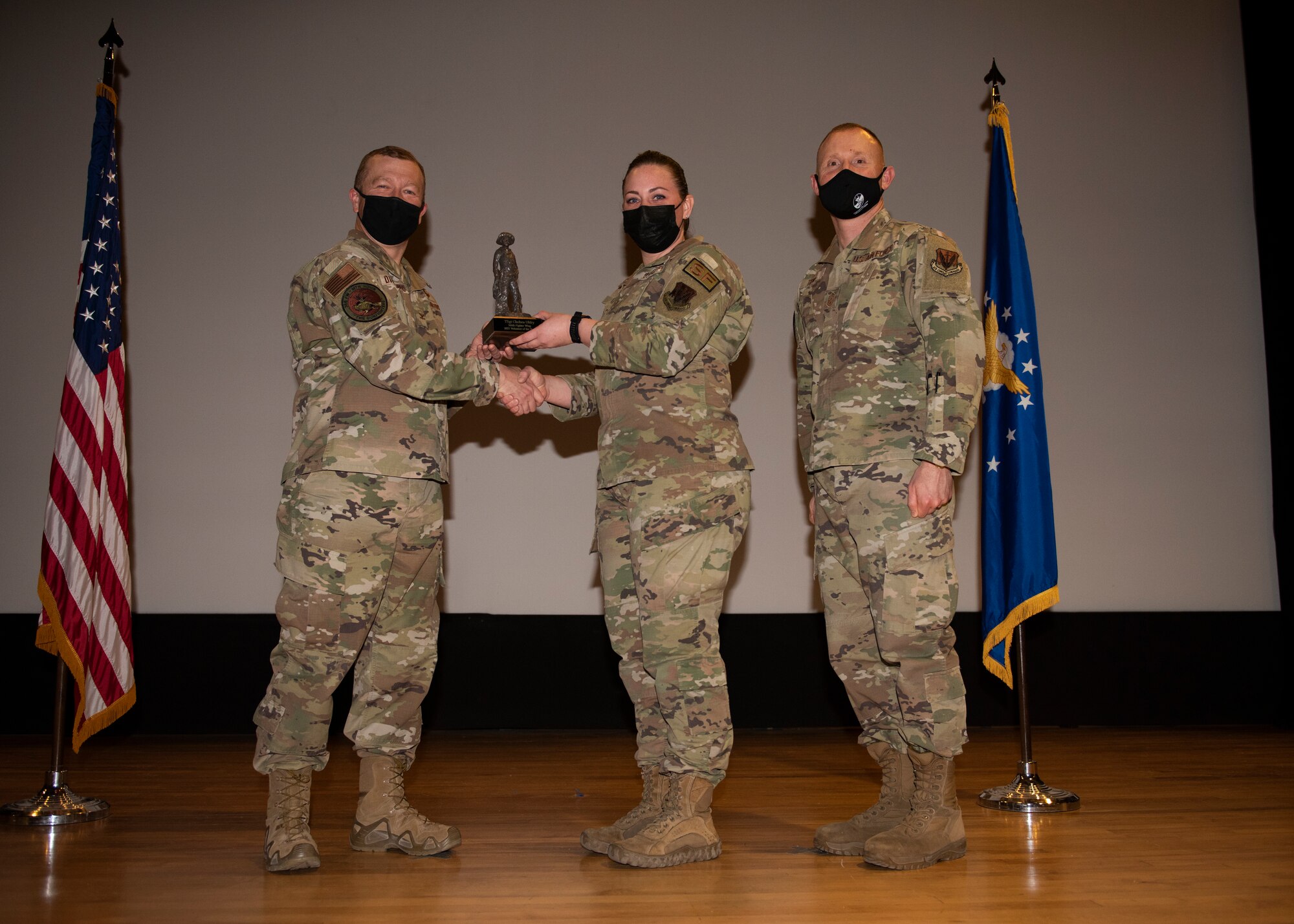 Three Airmen pose for a photo with a trophy.