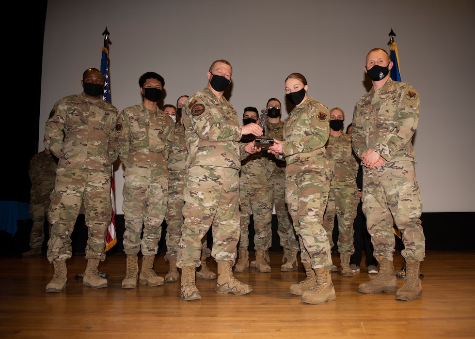 A squad of Airmen pose for a photo with a trophy.